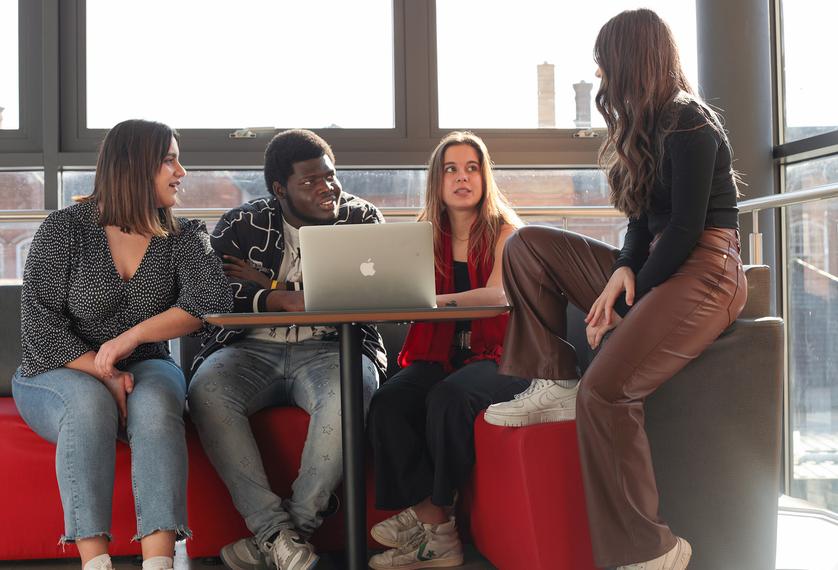 A group of postgraduate students chatting on sofa
