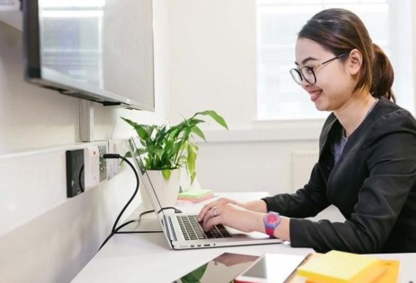 Female student sat at desk working on laptop
