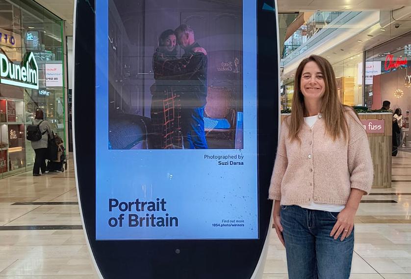 Woman stands next to billboard with image of couple