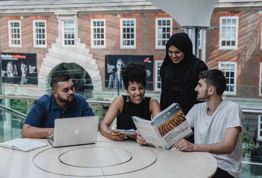 four business management students working together in the quad