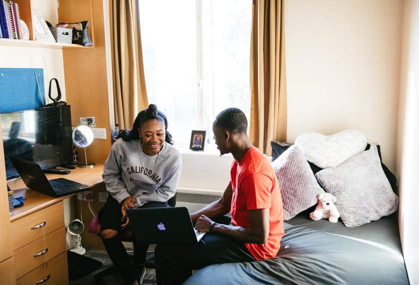 two students sit in bedroom studying together