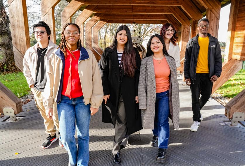 Six students walking together under a wooden structure