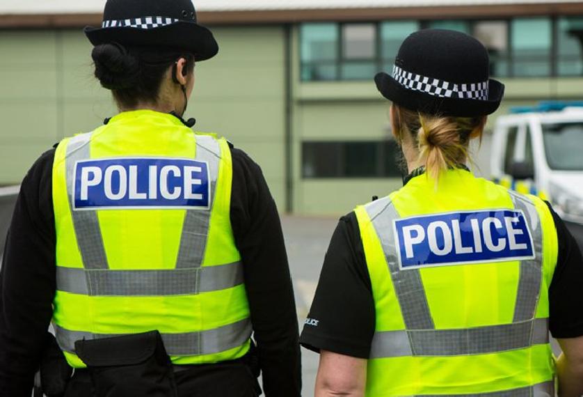 Two police officers standing side by side, wearing uniforms and looking alert.