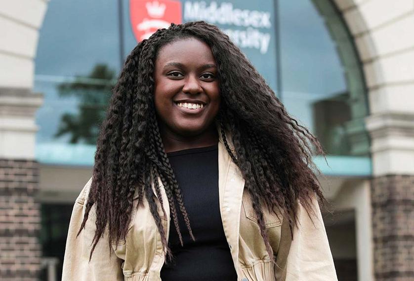 Student with curly long hair smiling at the camera