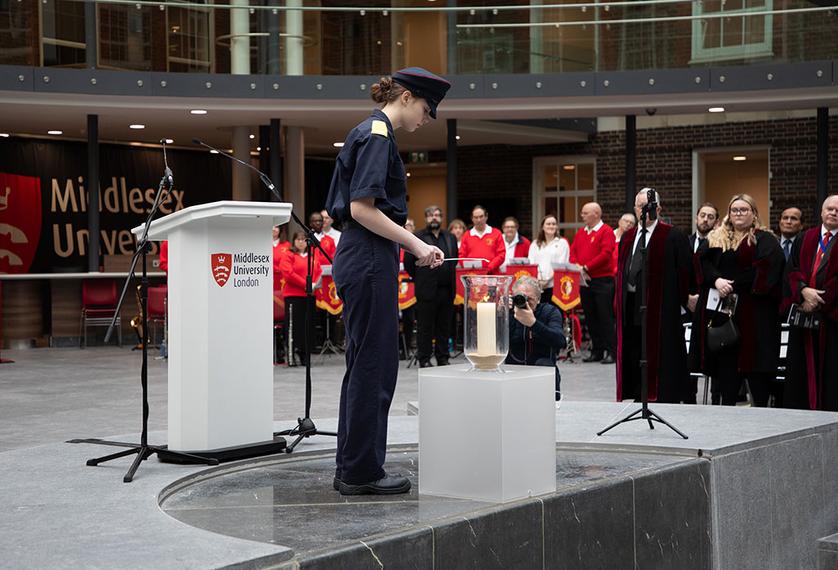 A cadet lights a candle at a memorial event