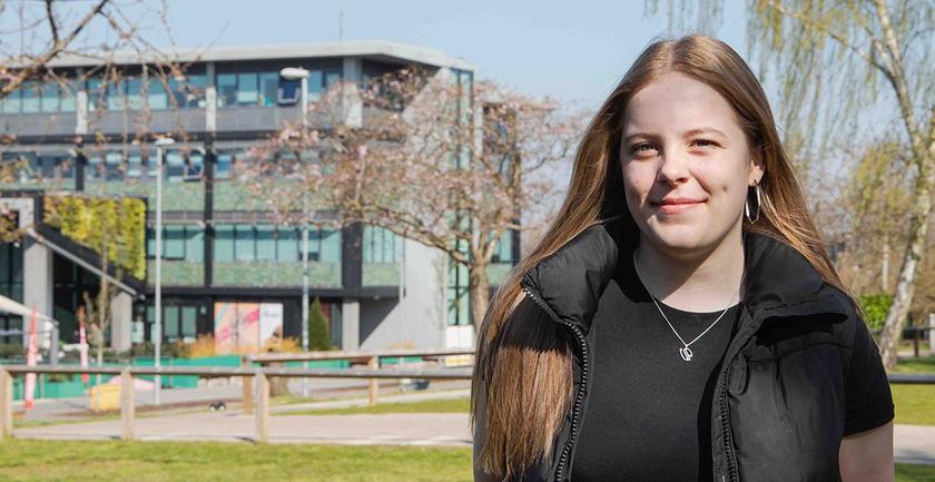 Abbi on campus on a sunny day with building in background