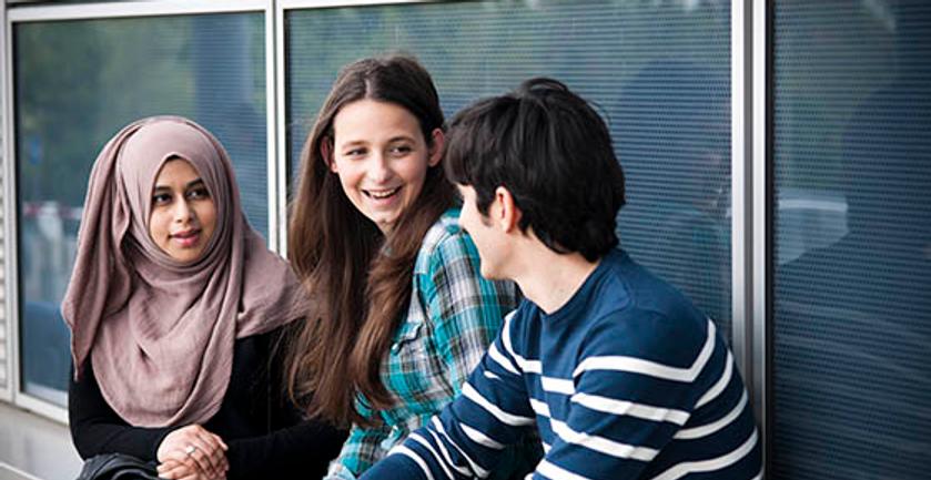 Three students on campus chatting.