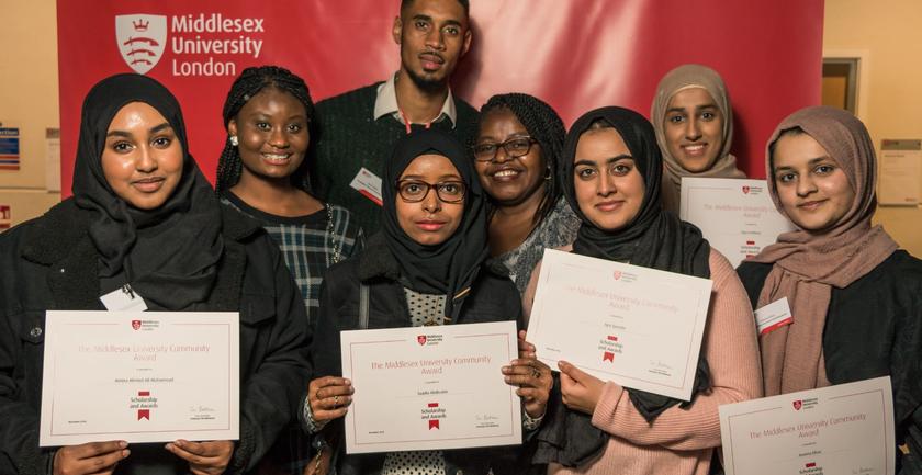 A diverse group of smiling young adults proudly holding up their certificates of achievement.