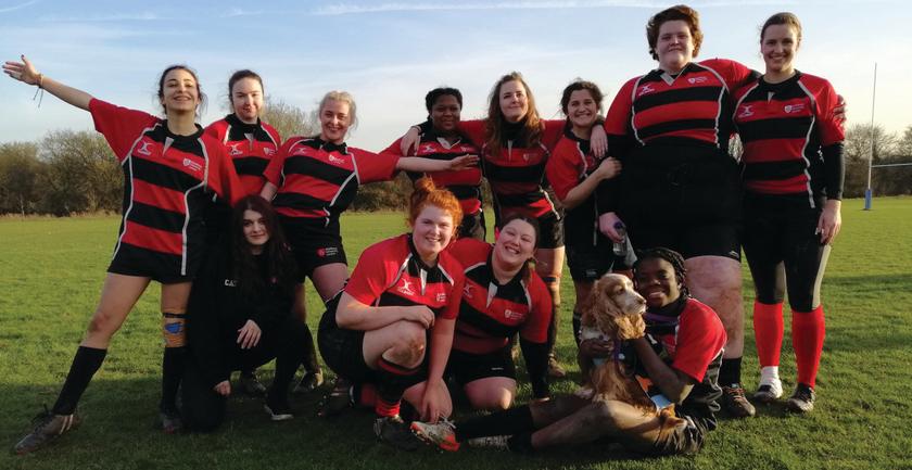 A group of women wearing red and black rugby uniforms, ready to compete in a match.