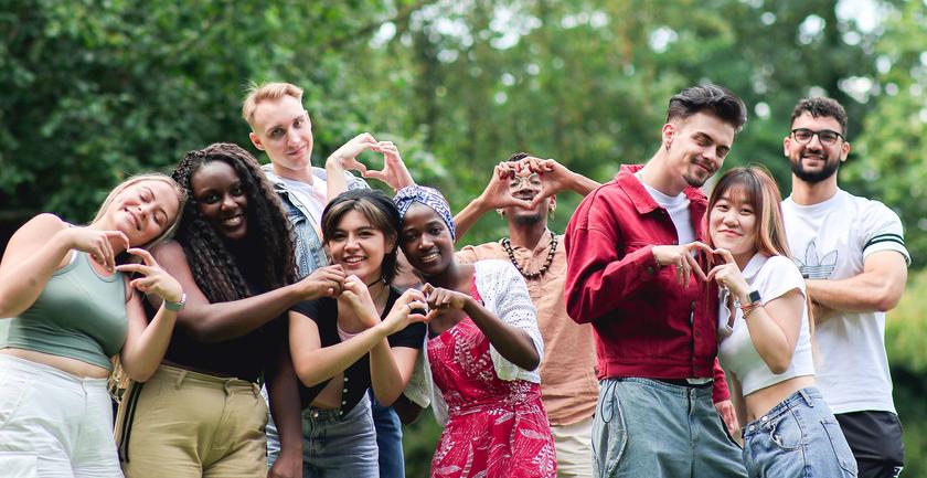 large group of happy students make heart shapes with their hands