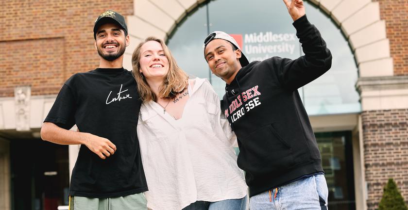 Three students stood together outside on campus