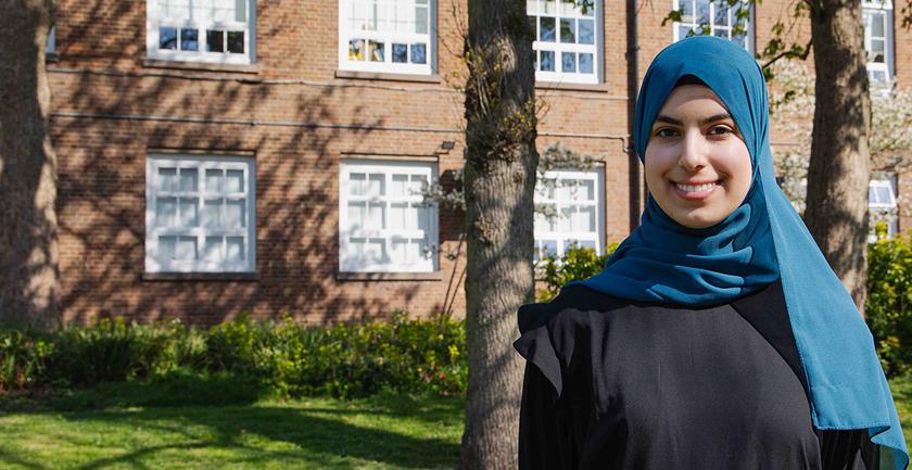 Duha stood on campus on a sunny day with campus building in background