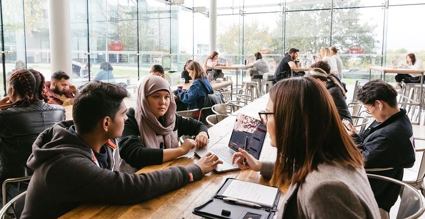 Students studying around a table in bright busy room