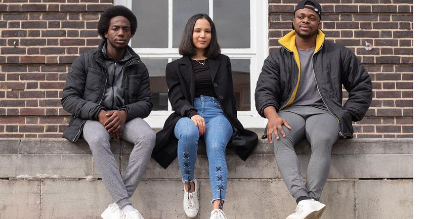 three students pose on campus, they look determined
