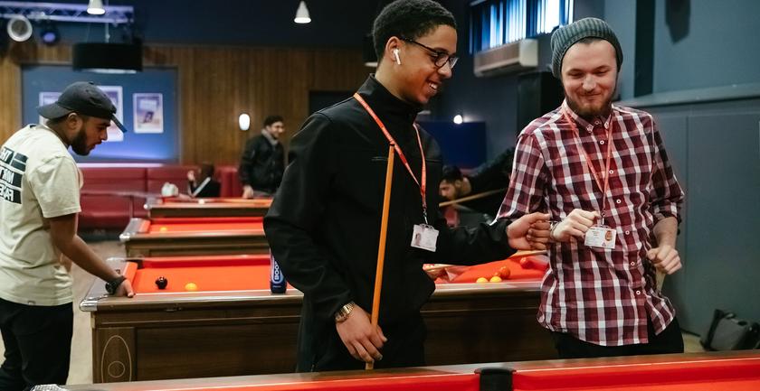 two students stand at pool table ready to play game