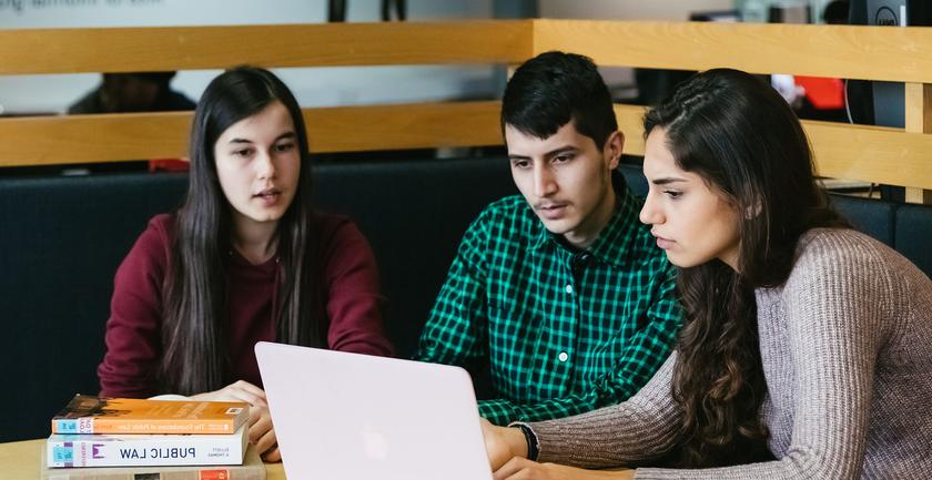 three students studying together in a library