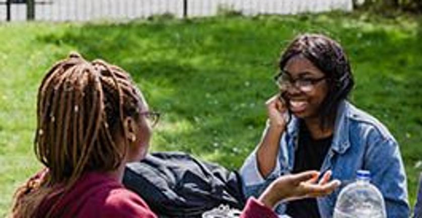 Three students studying at a table in the park
