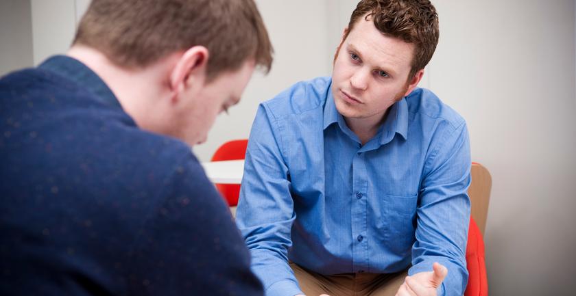 A person sitting on a couch talking to a therapist. They are engaged in a conversation about mental health and social work.