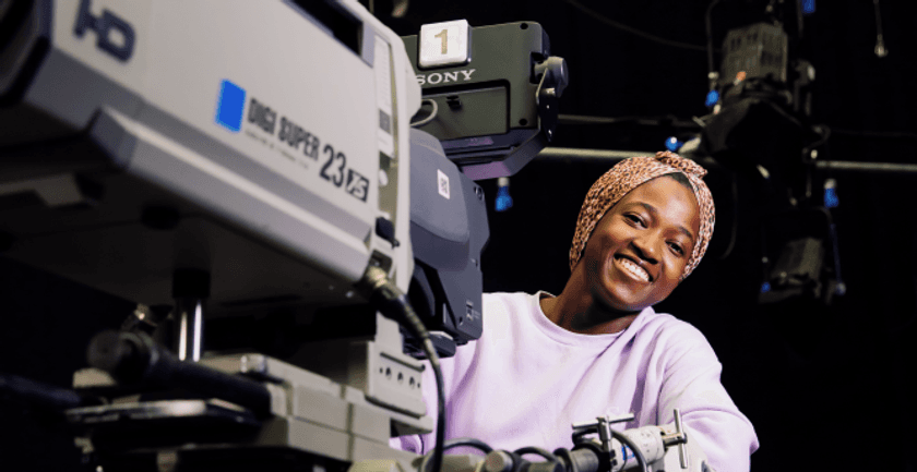 Female student with headscarf stands behind the  camera in the middlesex university tv studio