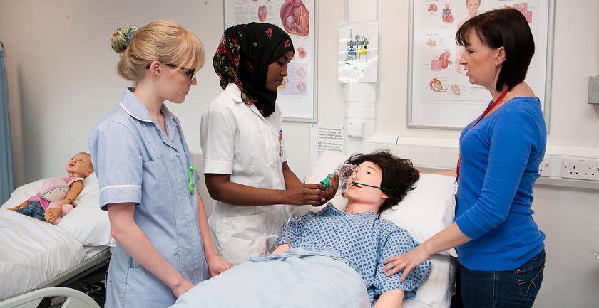 student nurses examining a dummy in class