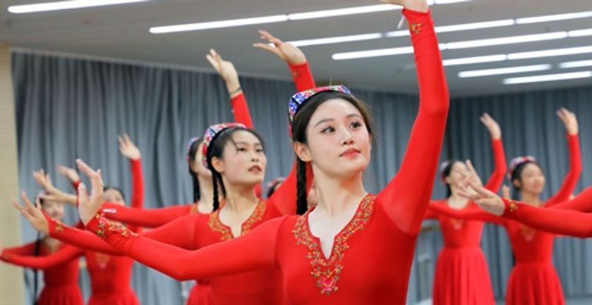 A group of Hainan students dressed in red dresses, dancing in a dance studio