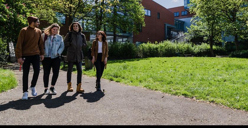 3 students walk together on middlesex university campus on a sunny day