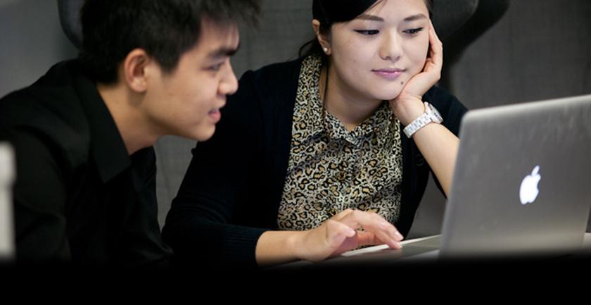 Two students sat at desk with laptop