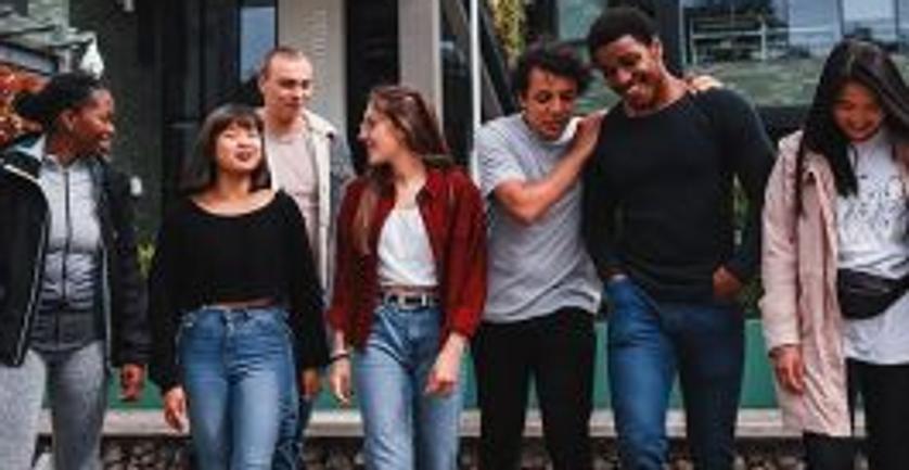 A diverse group of young adults walking together, laughing and chatting while enjoying a leisurely stroll