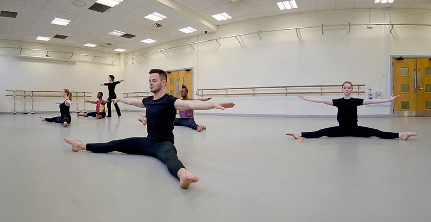 Six dance students performing the splits in the university's dance studio