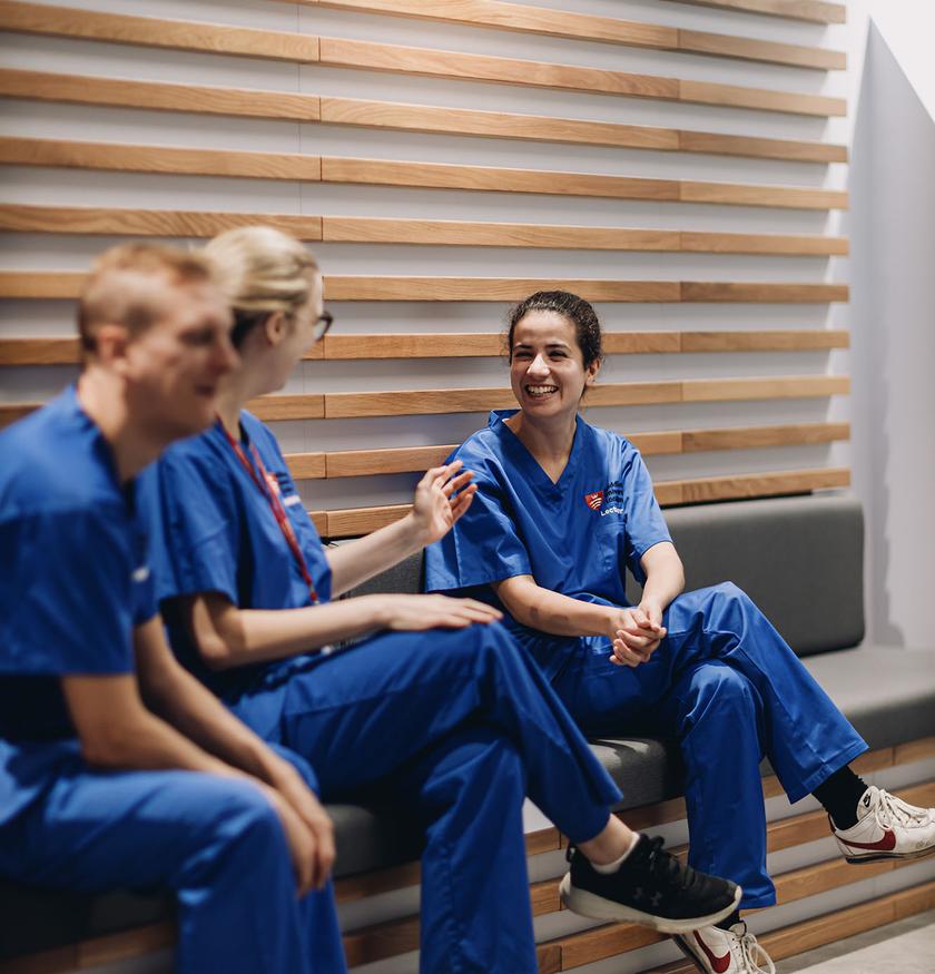 three nurses sit together chatting