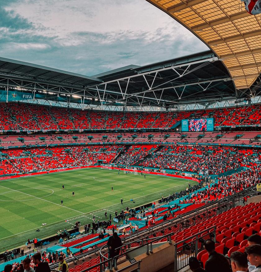 A packed Wembley stadium with a large crowd of people sitting in the stands.