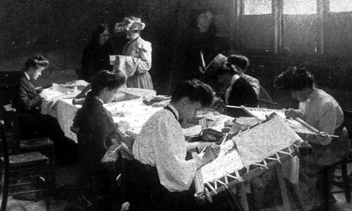 A black and white photo of several women sewing around a table. © Middlesex University