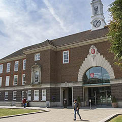 Student walking outside college building on a sunny day.