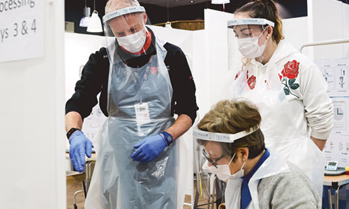 Two females and a male wearing PPE are looking at testing material in a processing bay. © Middlesex University