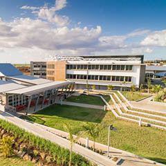 A modern builing complex set in a grassy landscape with blue sky and sunshine