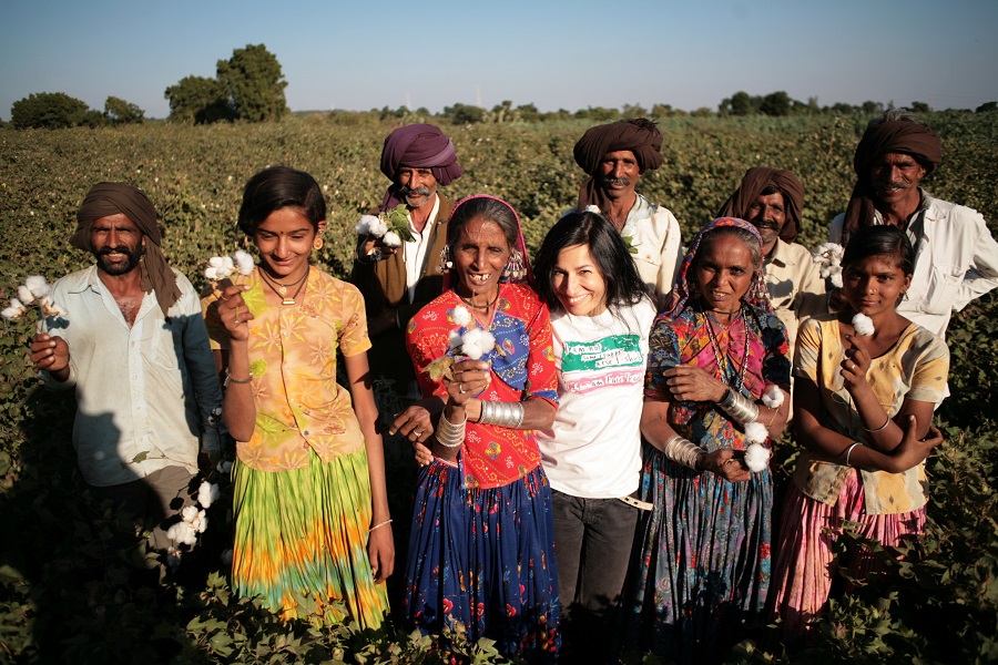 A diverse group of individuals standing in a field, holding cotton in their hands.