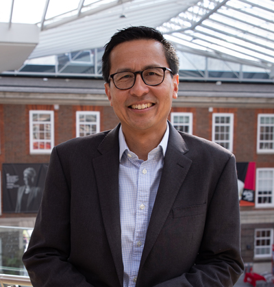 A portrait of Byron Hoo in the Atrium of of a �鶹TV��վ University building with a glass ceiling and lots of windows behind him