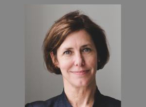 A portrait of Carol Osbourne against a grey background