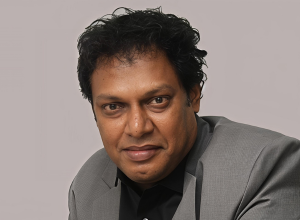 Portrait of Dr K.K. Ramachandran in a grey suit against a grey background