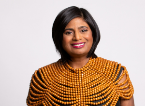 A portrait of Sharmla Chetty wearing a golddress against a white background