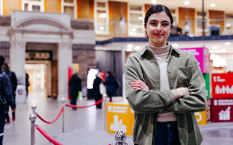 A woman standing confidently in a mall with her arms crossed.
