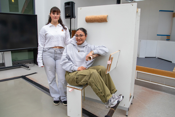 Two women in a studio showing off their work