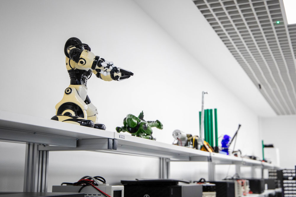 Two small robots displayed on top of a stand, viewed from below.