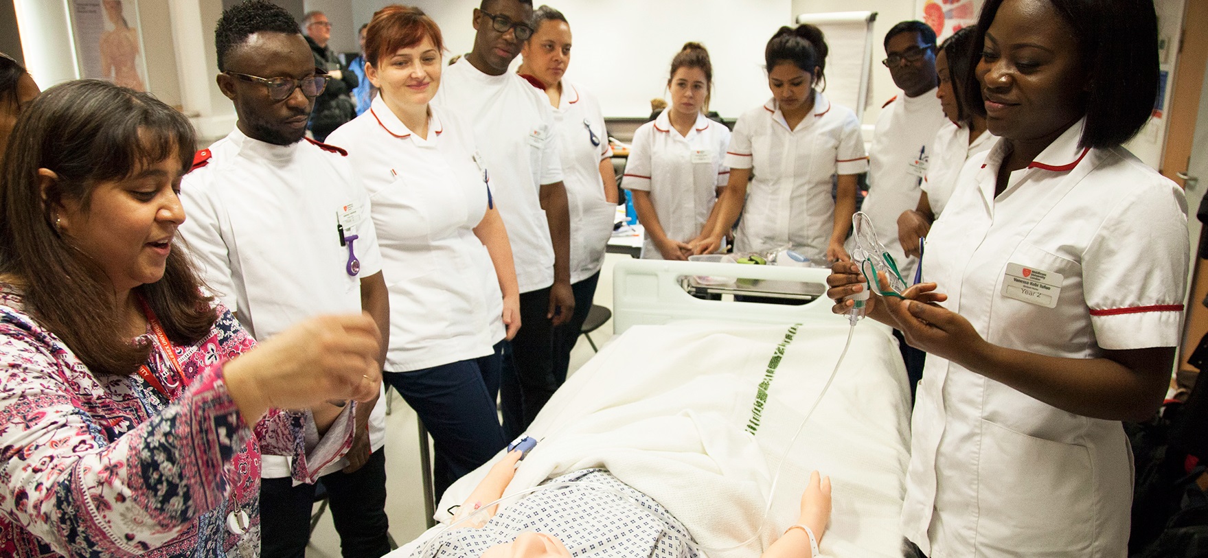 Nurses gathered around a medical mannequin for training in a hospital.