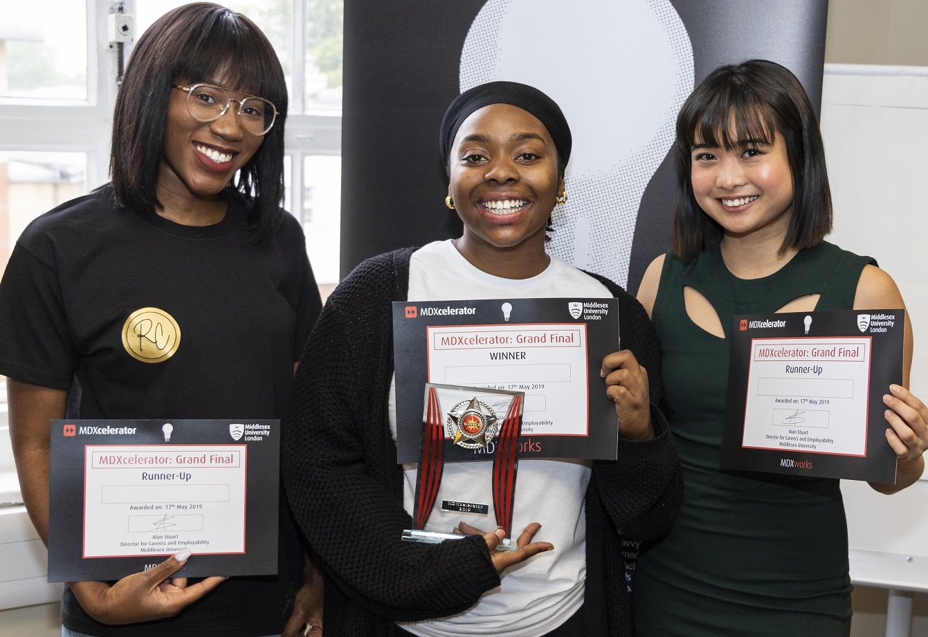Three female student displaying their MDXcelerator certificates
