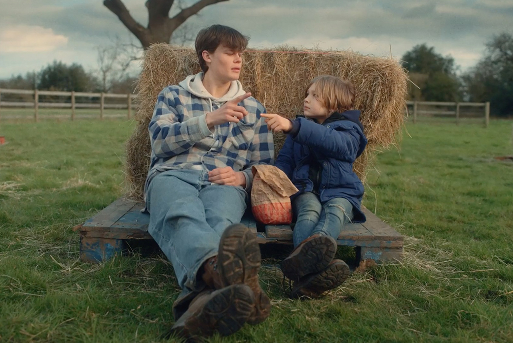 Two brothers sat on hay bale