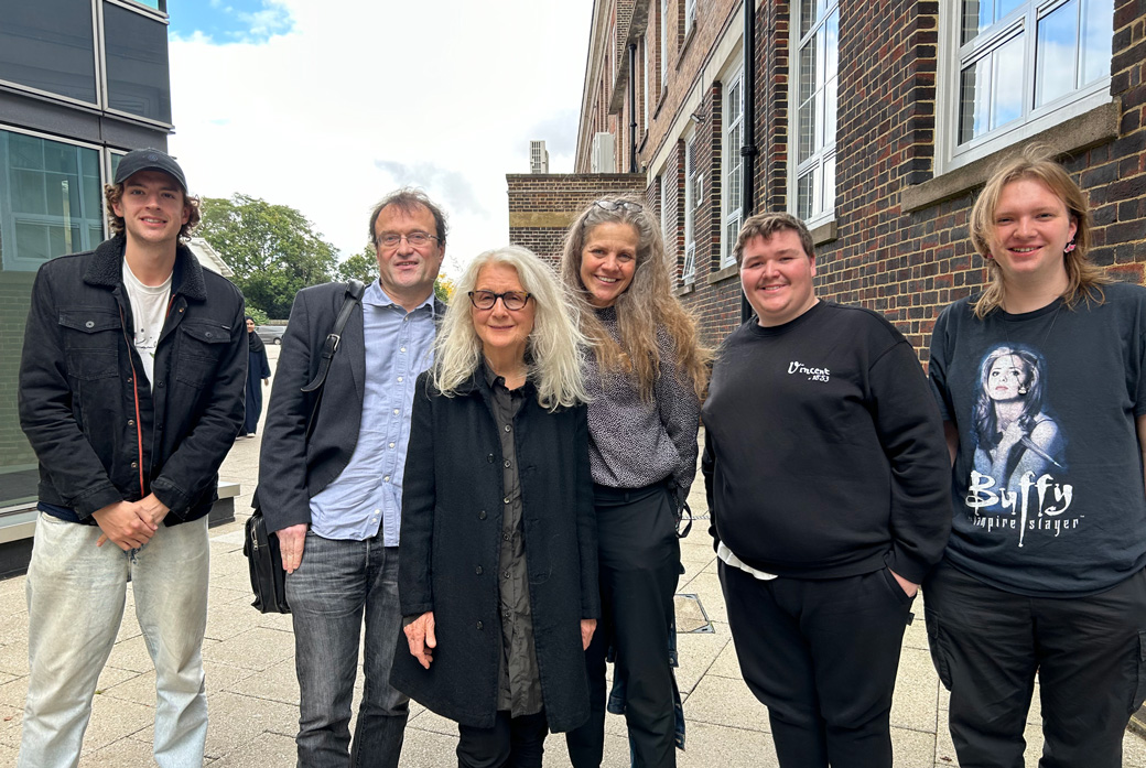 Group of diverse age people standing in front of an old red brick building.