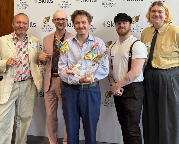 A line-up of Middlesex Animation students and staff members at an award ceremony. Arturs the director of the winning Animation stands in the centre holding three awards