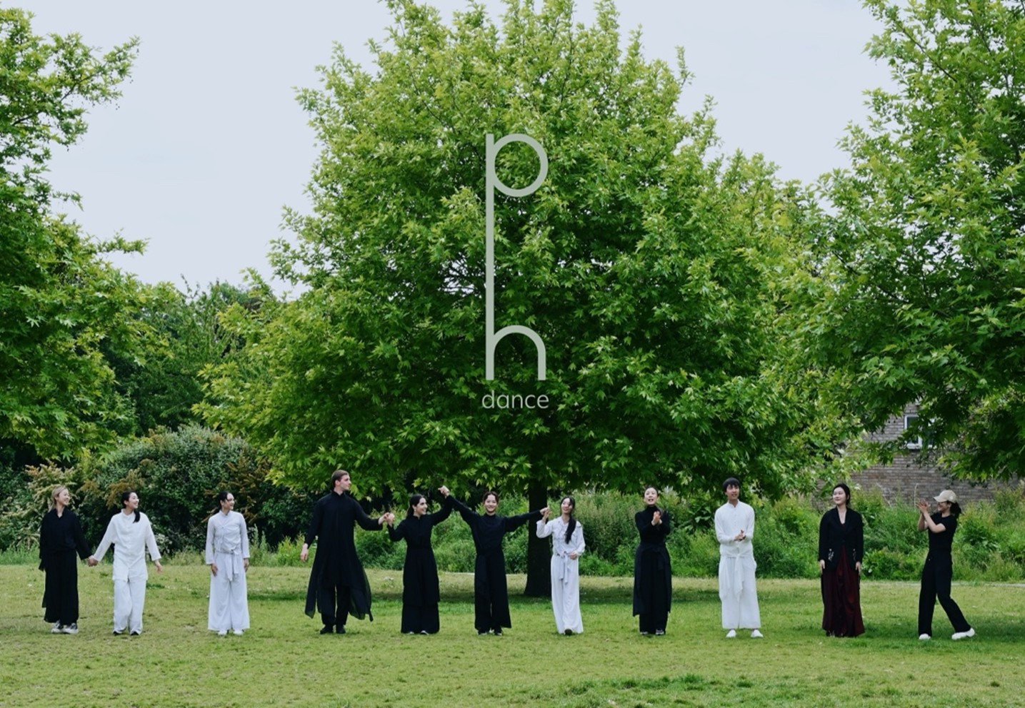 A line-up of dancers in the Resonant Space show wearing distinctive long black and white costumes