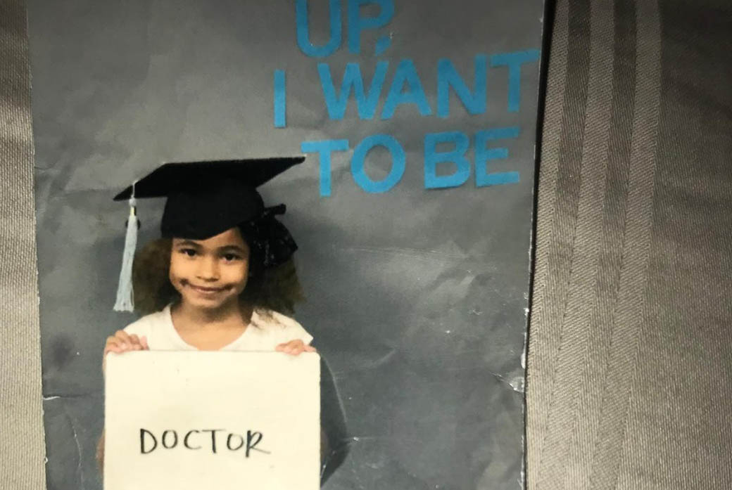 A girl holds a sign saying 'doctor'